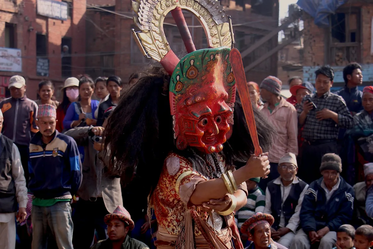 A masked Lakhey dancer performing before a street crowd at a festival in Nepal