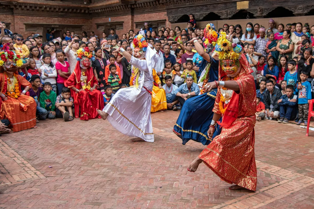 Dancers performing before a large seated community crowd in a Nepali town square